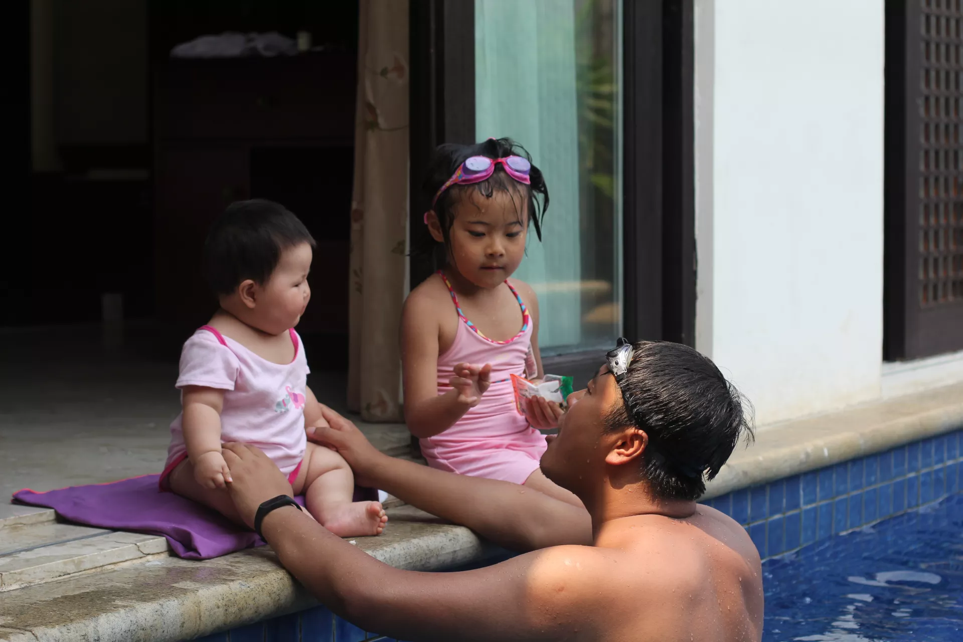 一位父亲陪两个女儿游泳。