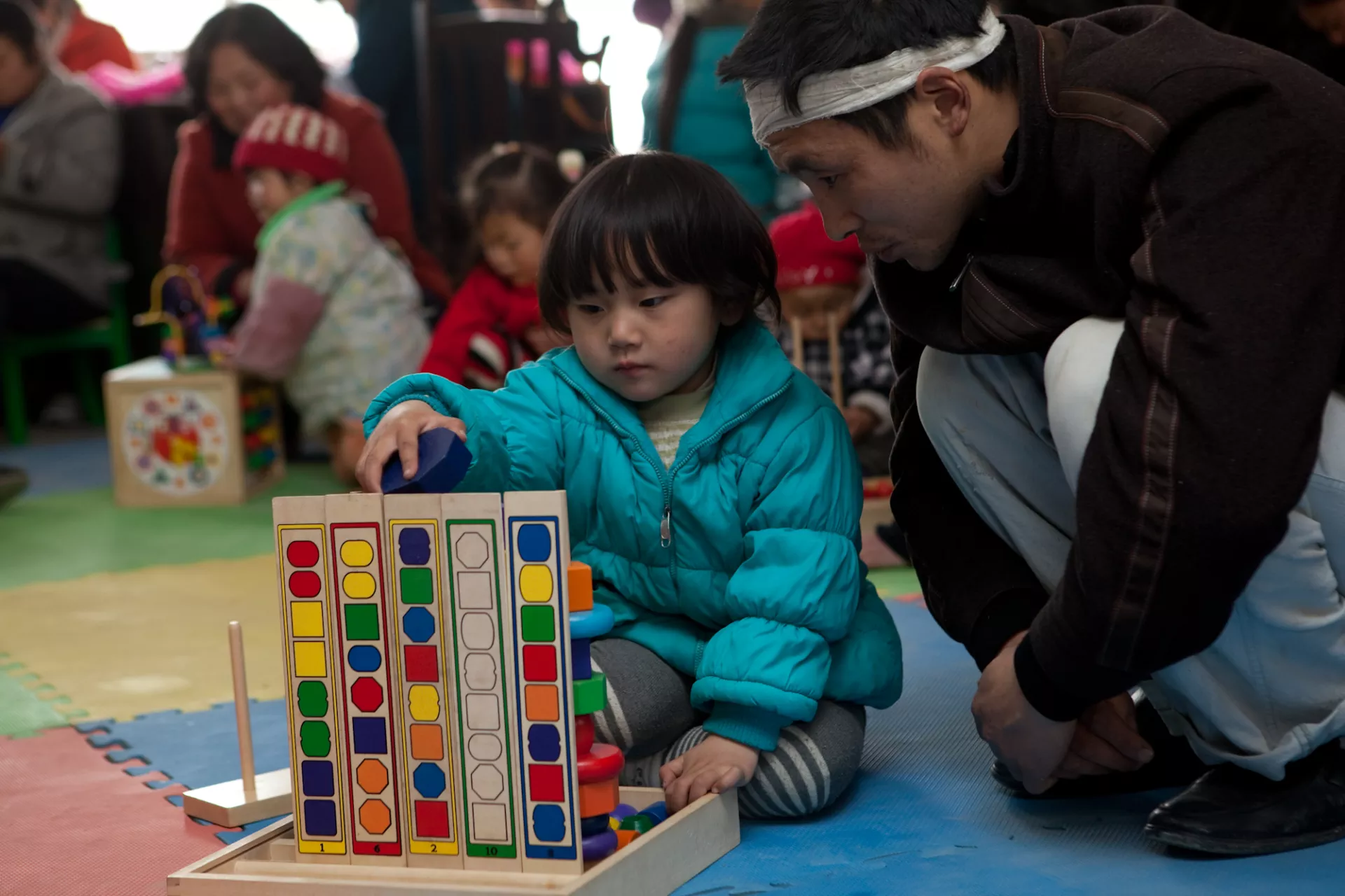 A father watches his daughter playing with toy bricks at Shengli Child-Friendly Space in Leigu, Sichuan Province.