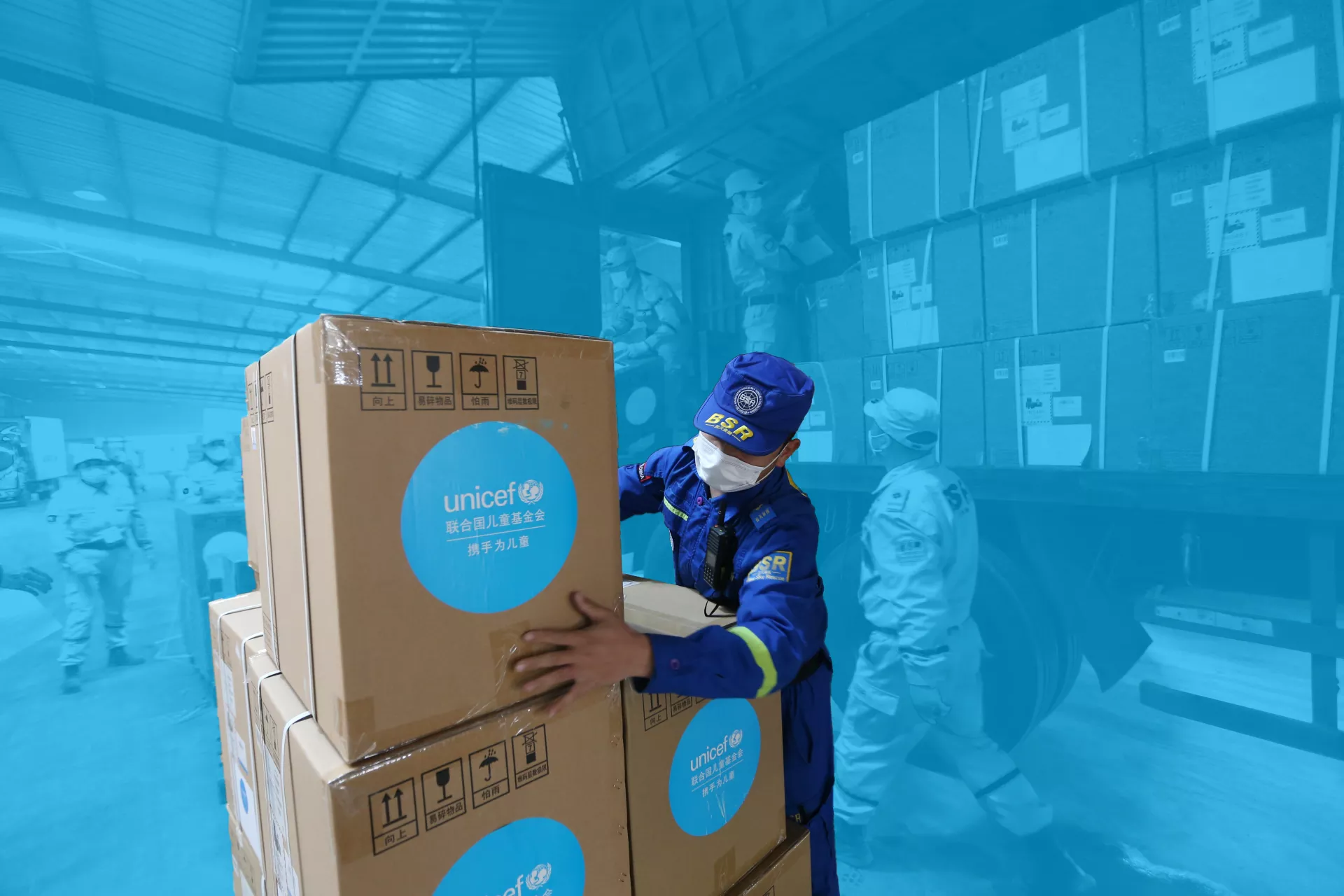 2020年3月18日，在武汉市湖北省慈善总会疫情防控捐赠物资联合应急仓库里，志愿者们搬运由联合国儿童基金会捐赠的物资。
