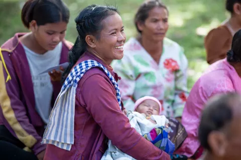 A mother and children participate in a community village activity with healthcare workers.