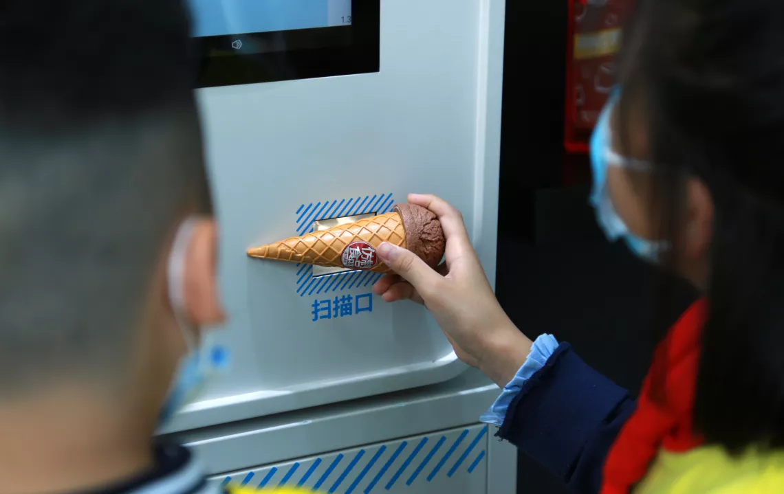 At the self-checkout counter, a girl scans an ice-cream to view the amount of sugar, fat and energy it contains.