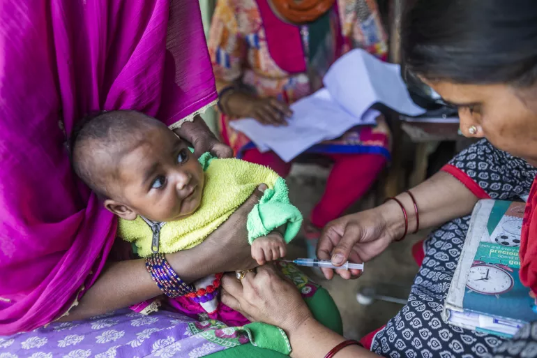 在印度一所农村卫生保健中心内，一名助产士为孕妇和儿童进行脊髓灰质炎疫苗接种。