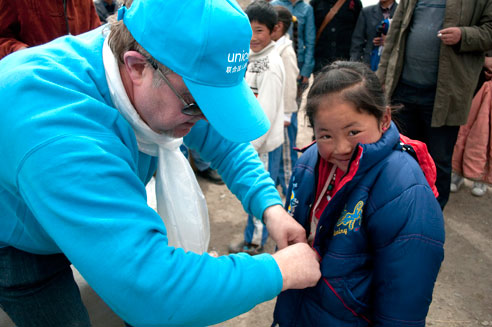 2010年5月11日，联合国儿童基金会评估小组成员在称多县中心完小察看并向孩子们分发刚刚抵达的儿童防寒服、棉裤和袜子