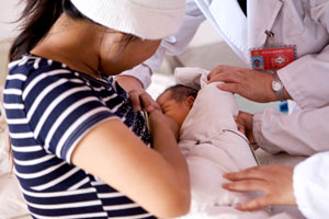一位母亲在医护人员的指导下为孩子进行母乳喂养。