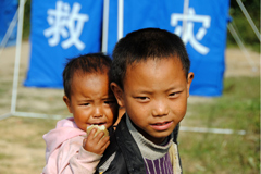 在云贵交界处发生的地震摧毁了上千所房屋，图为两名儿童在帐篷前玩耍。