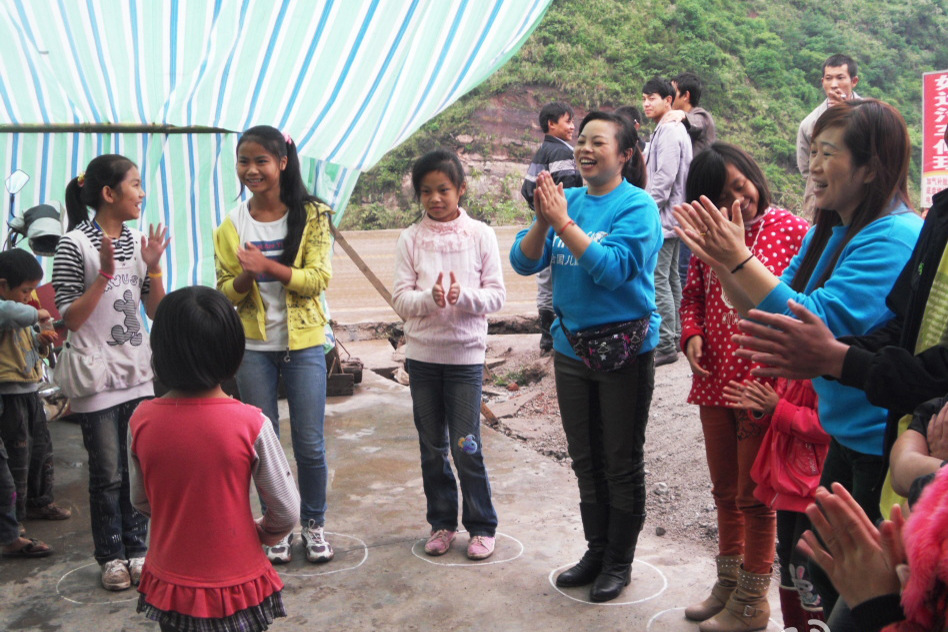 来自四川的儿童友好家园志愿者在彝良和孩子们一起做游戏。