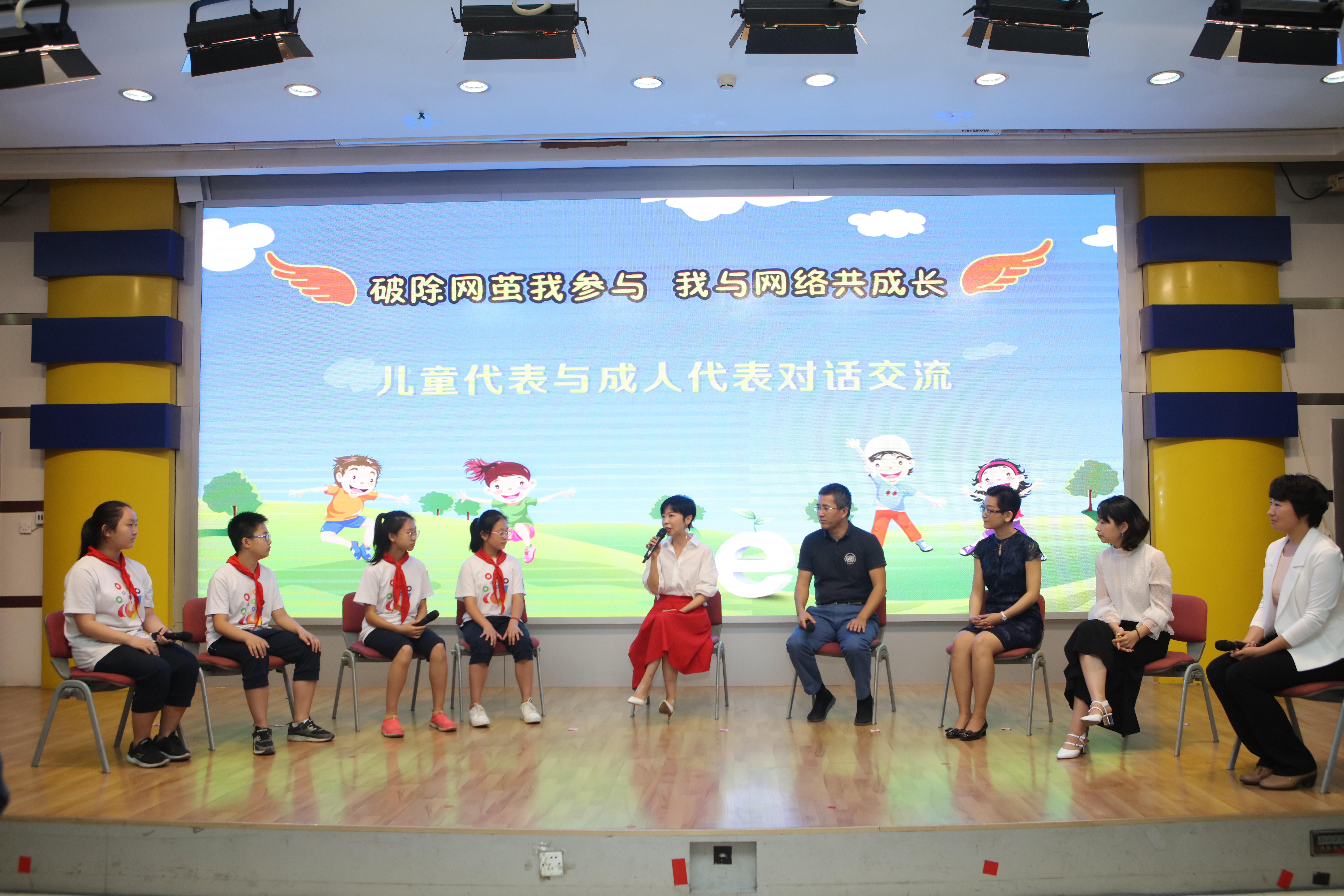 2018年6月1日，在“破除网茧我参与，我与网络共成长”六一儿童论坛上，北京市东城区东四十四条小学的学生祝松岳（左四）、王越辰（左三）、孔德浩（左二）和刘嘉祎（左一）与联合国儿童基金会驻华办事处儿童保护官员苏文颖（中）、北京青少年法律援助与研究中心主任佟丽华（右四）、中国传媒大学教育研究中心副研究员张洁（右三）、腾讯安全课高级讲师舒梦莹（右二）、家长代表王迎（右一）展开对话，就他们对网络的看法畅所欲言。