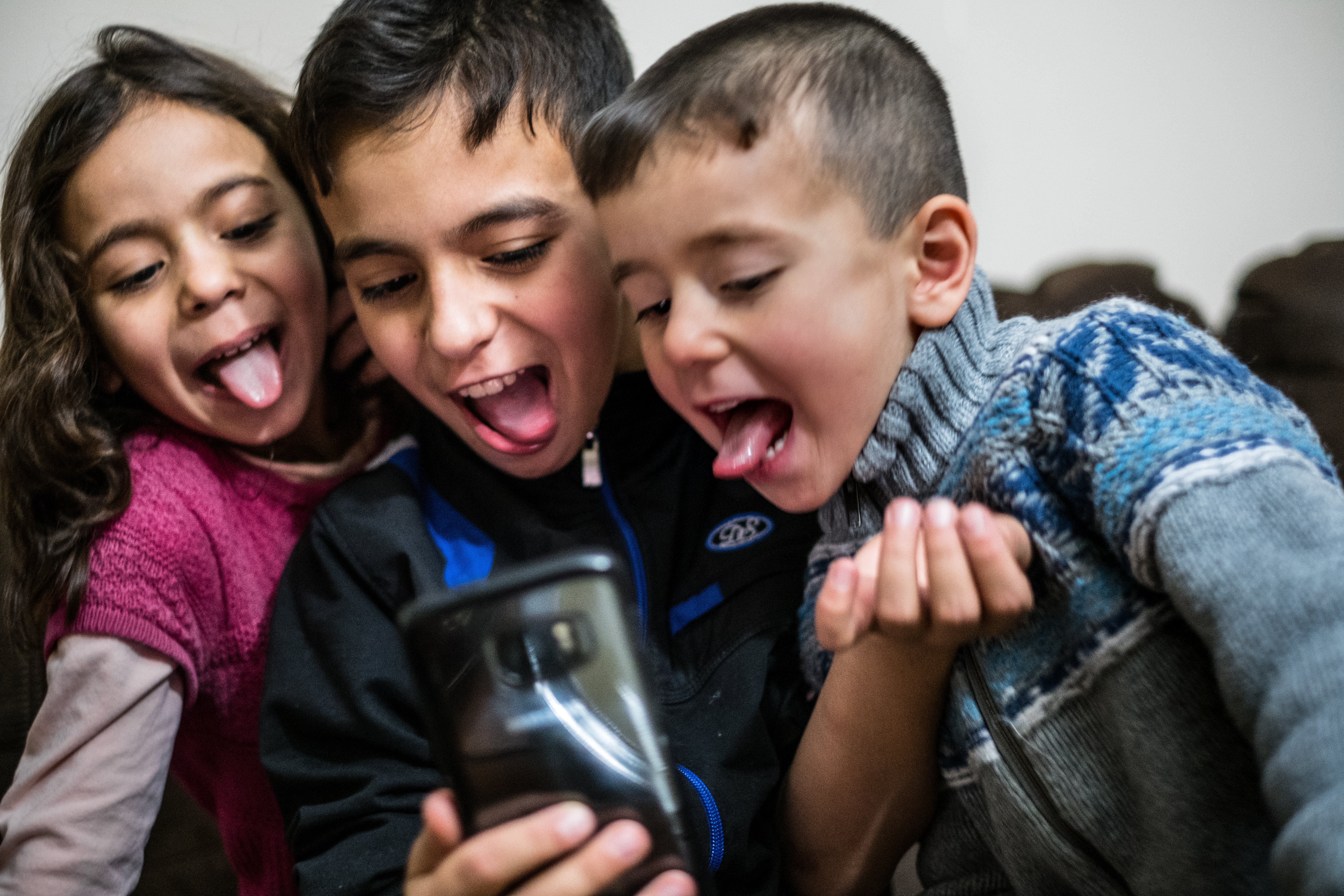 2016年12月12日，11岁的Basel Al Rashdan，7岁的Shatha Al Rashdan和5岁的Idress Al Rashdan在Canada，Prince Edward Island，Charlottetown的家中玩妈妈的手机。