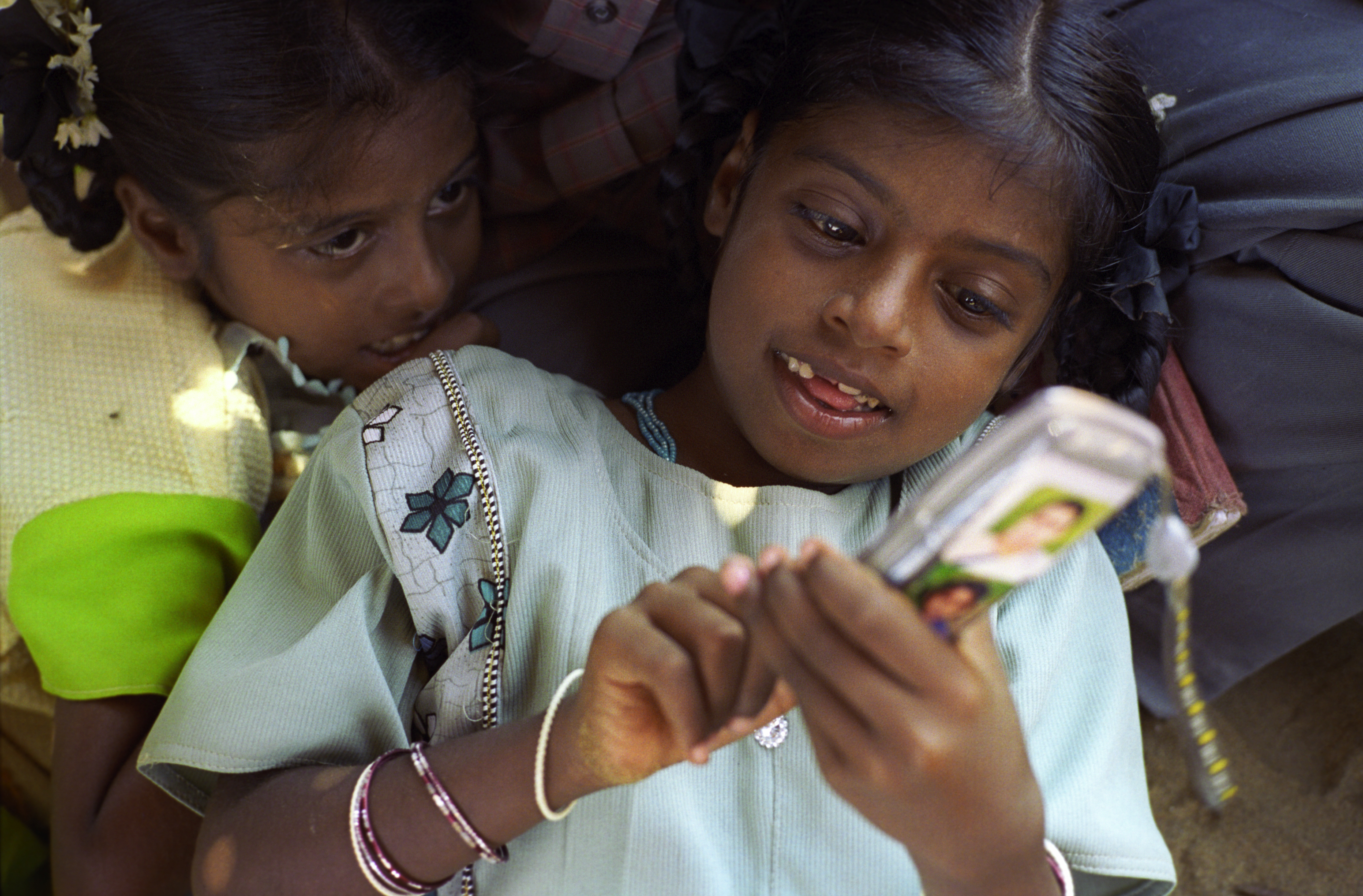 9岁的Vijitha Viswanathan（身着绿衣）看她的姐姐玩父亲的移动电话。