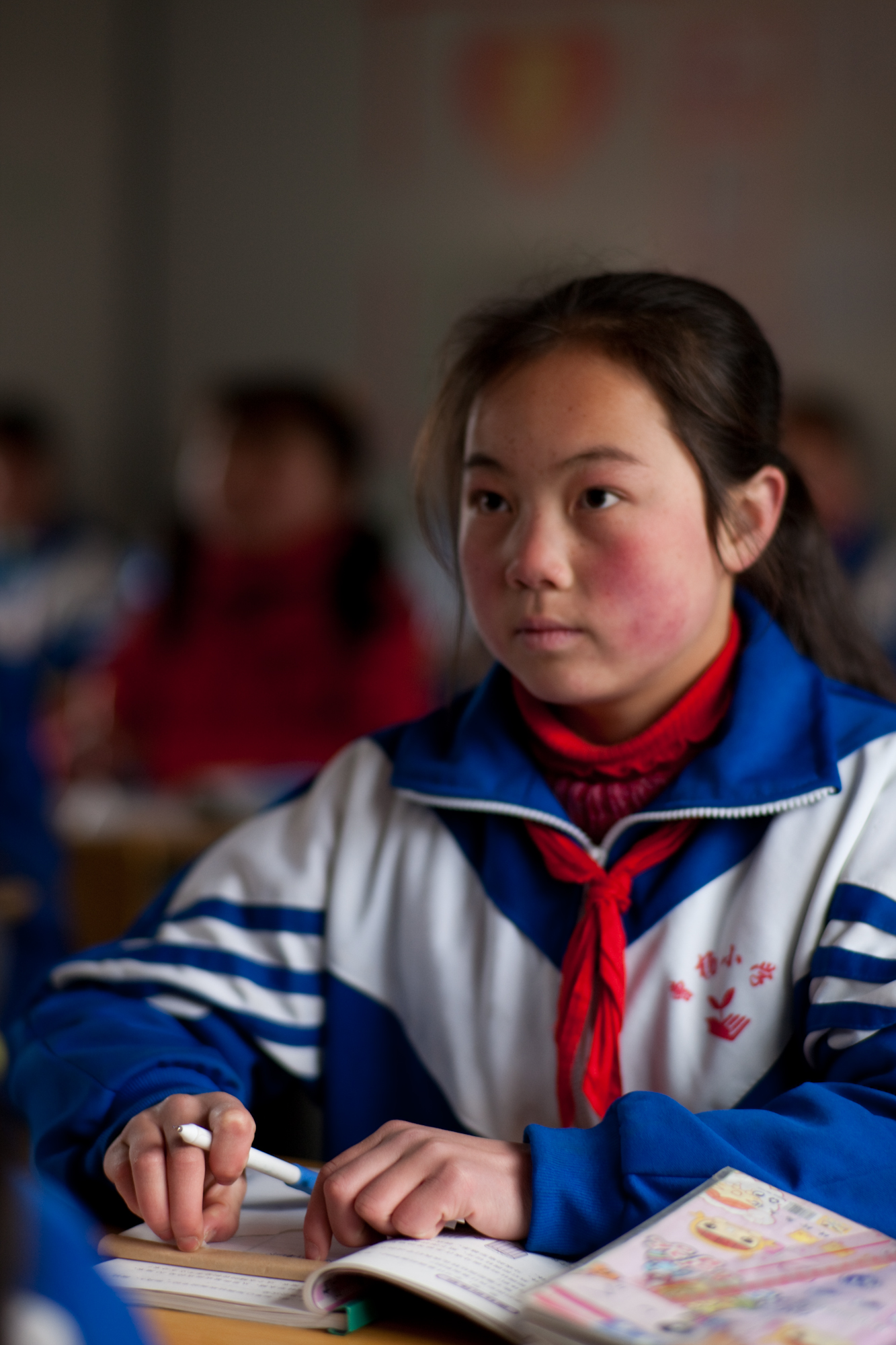 六年级小学生杨媚坐在联合国儿童基金会提供的板房教室内认真地听老师讲课。