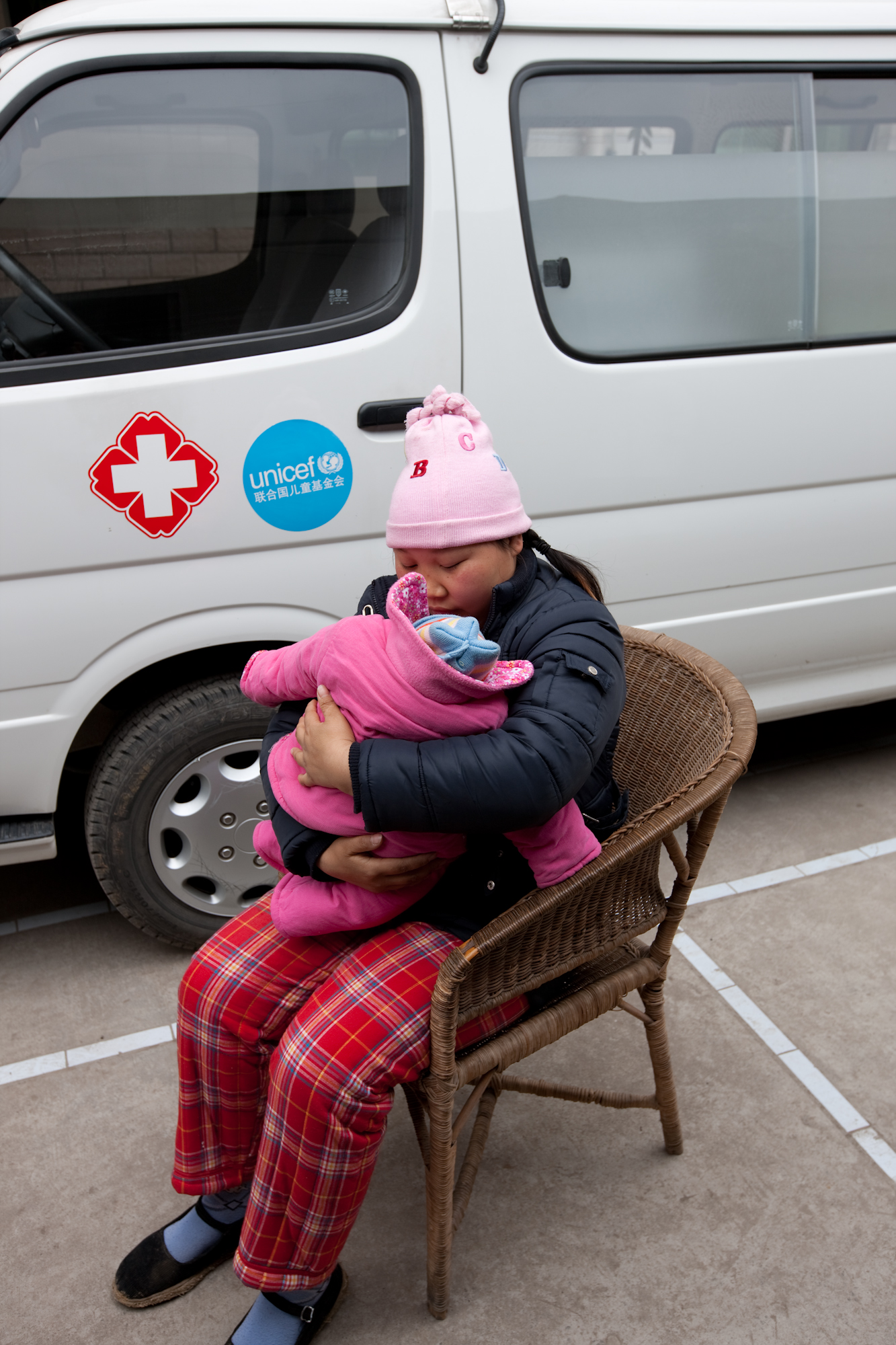 刘菊抱着孩子坐在救护车前，十天前，就是在这辆由联合国儿童基金会提供的救护车里，她生下了孩子。
