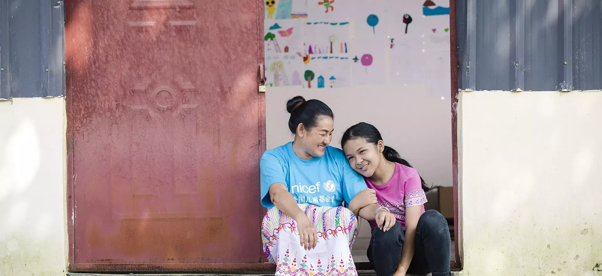 云南盈江，一名社工和一名女孩坐在村里儿童之家的门口。