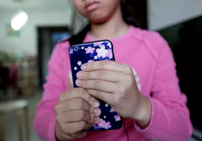 一名小女孩握着手机。