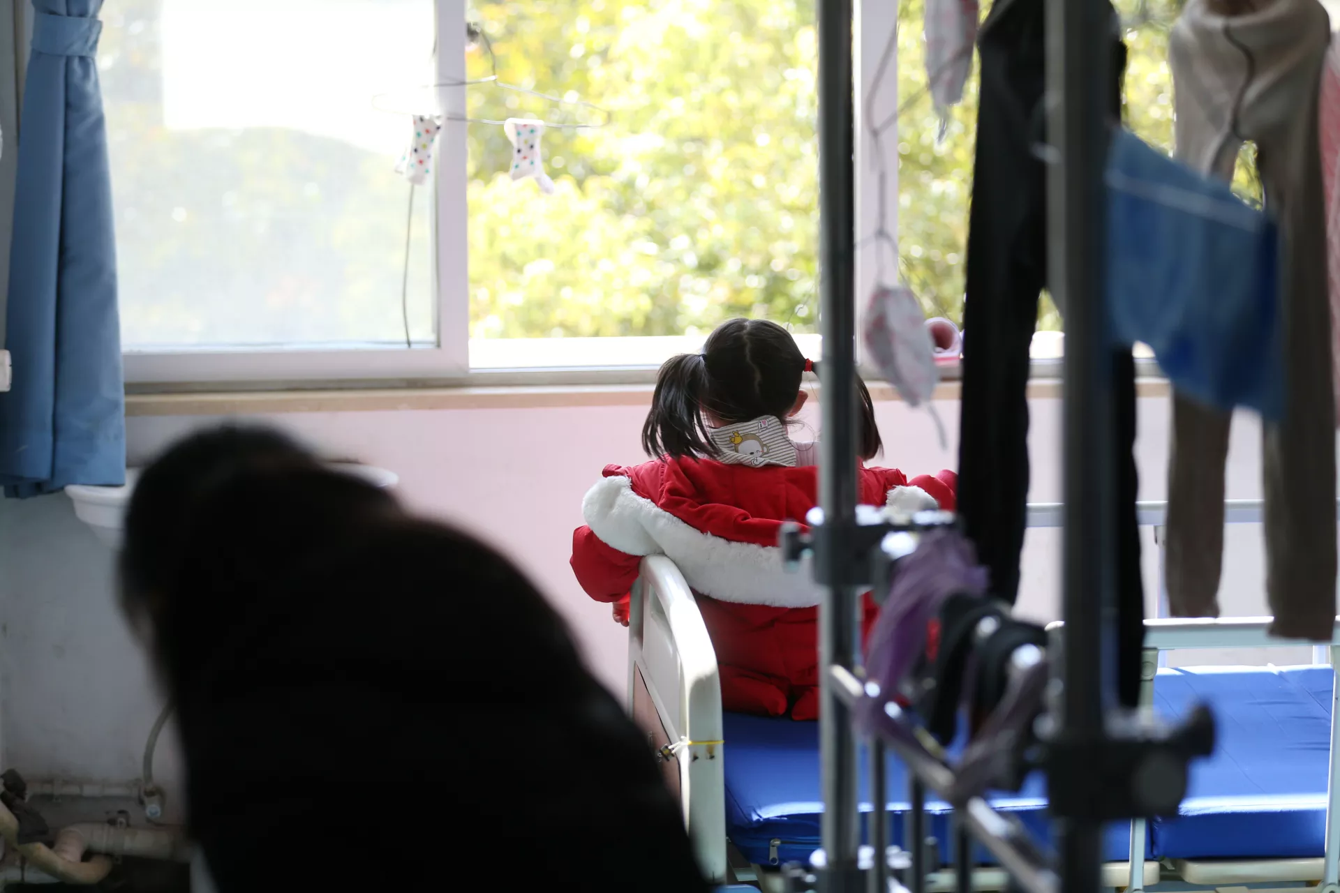 Five-year-old Yuanyuan* looks out the window of her room in a hospital affiliated to the Wuhan University of Science and Technology on 17 February 2020.