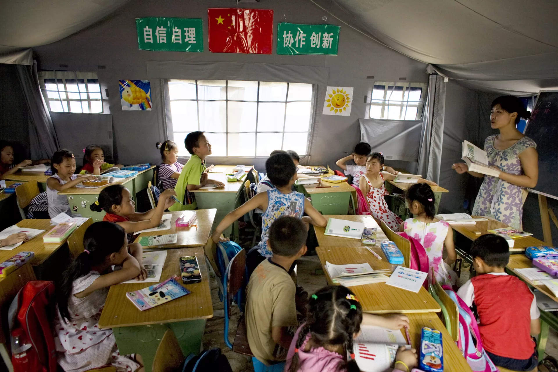 Children attend school in a tent classroom in the city of Mianyang in Sichuan Province. UNICEF has provided portable latrines at the temporary school. The city is in one of the areas hardest hit by the earthquake.