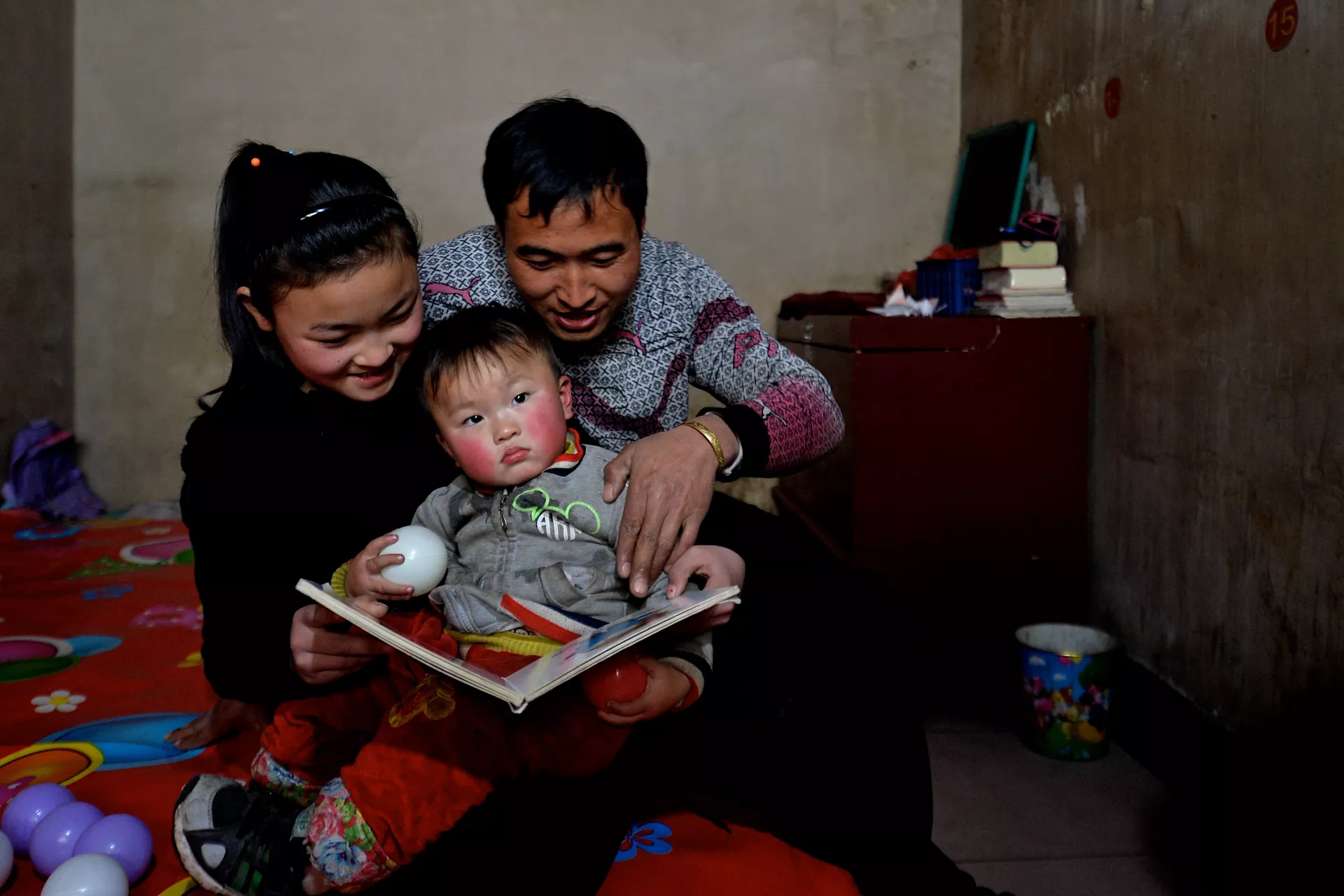 A father reads a story to his children at their home in Fenxi County, Shanxi Province, in 2017.