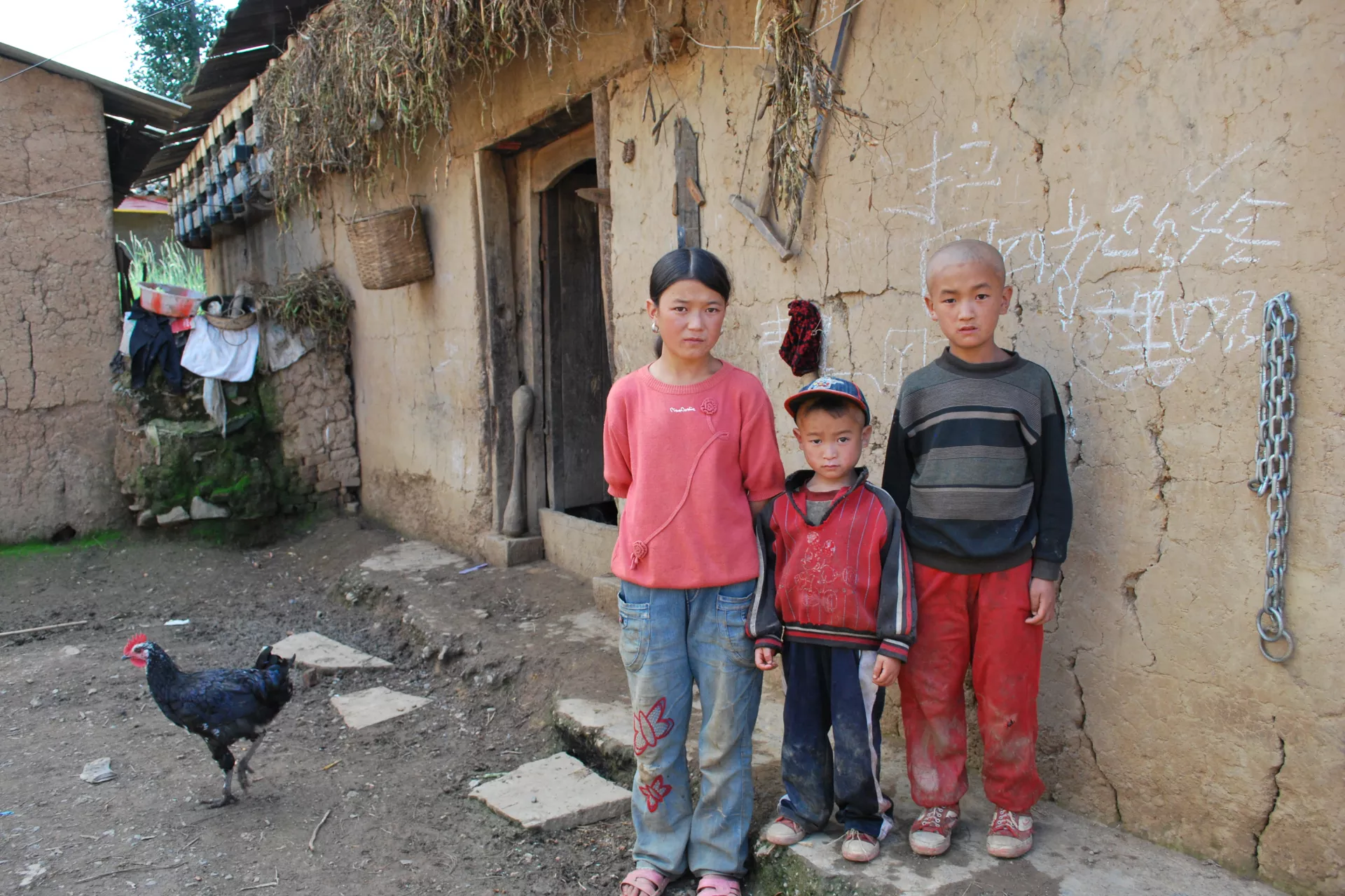 13-year-old Jiwu (1st Left) and her younger brothers stand in front of their house in this photo taken in early September, 2010.