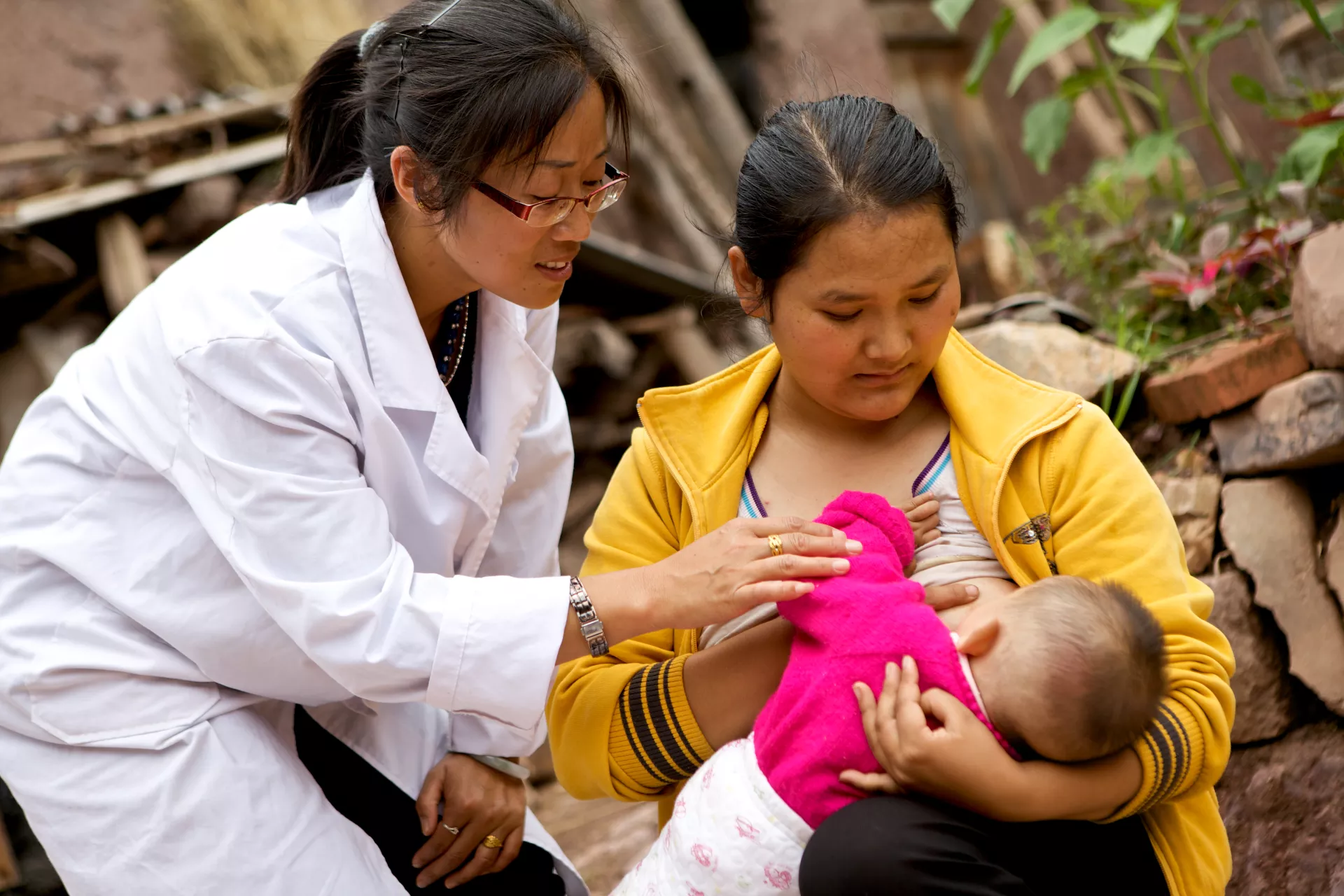 A woman breastfeeds her child under the guidance of a health worker in Wuding County, Yunnan Province, in 2011. 