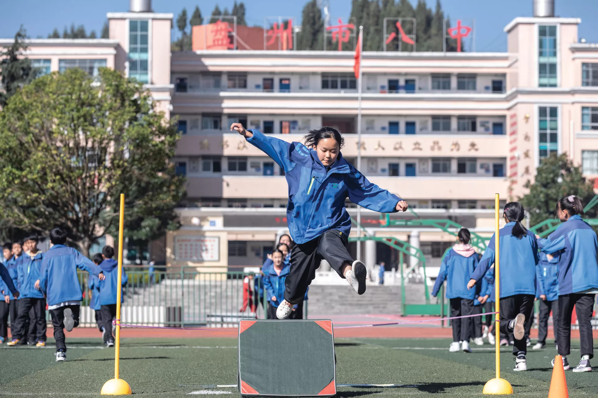A girl jumps over a barrier during a PE class at a middle school in Panzhou, Guizhou Province, in November 2020.