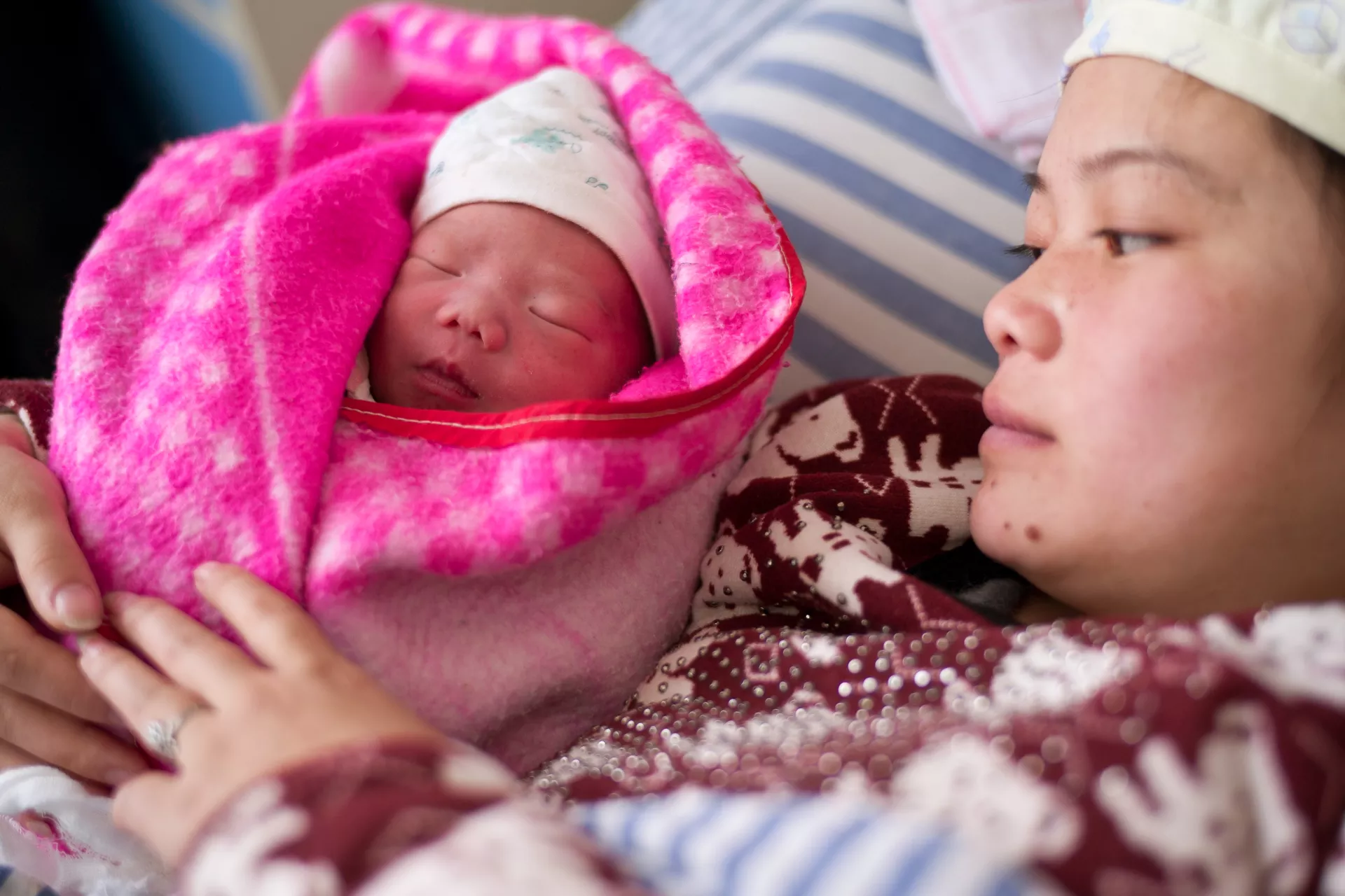 A mother holds her new-born baby in a hospital.