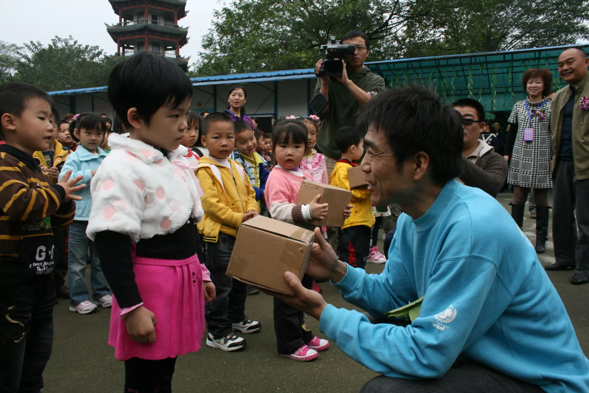 Dr. Yang Zhenbo (in blue), UNICEF China's Water, Sanitation and Hygiene Specialist, presents a UNICEF-provided hygiene kit to a girl in Shifang City Second Kindergarten in Sichuan Province at an event on the Global Handwashing Day in 2009.