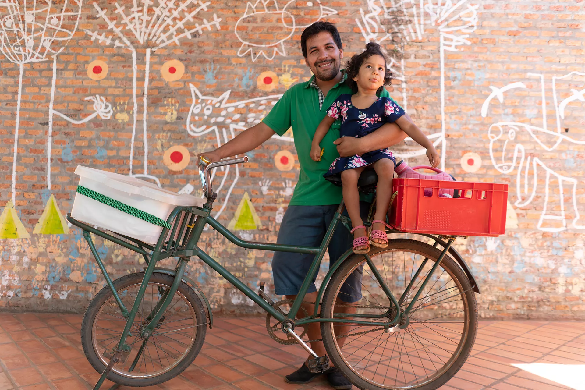 Rafael Alfonso Araujo, 27, holds his daughter Selva, 2, atop the bicycle that serves as the family's transportation and mobile food-sales cart at the Torore center in Areguá, Central department, Paraguay, 28 January 2019.