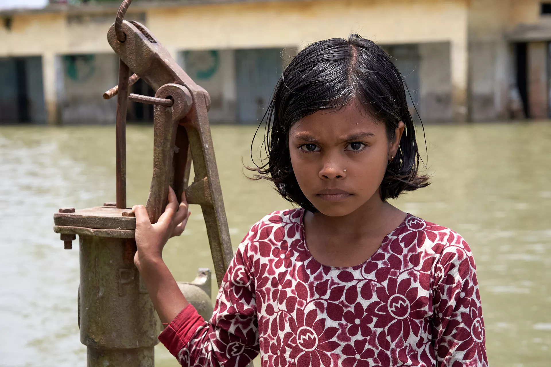 Ishrafi Khatun (10) stands in front of her school, Borobari Govt. Primary in Bangladesh, that has been submerged under water for the past few days due to severe flood.