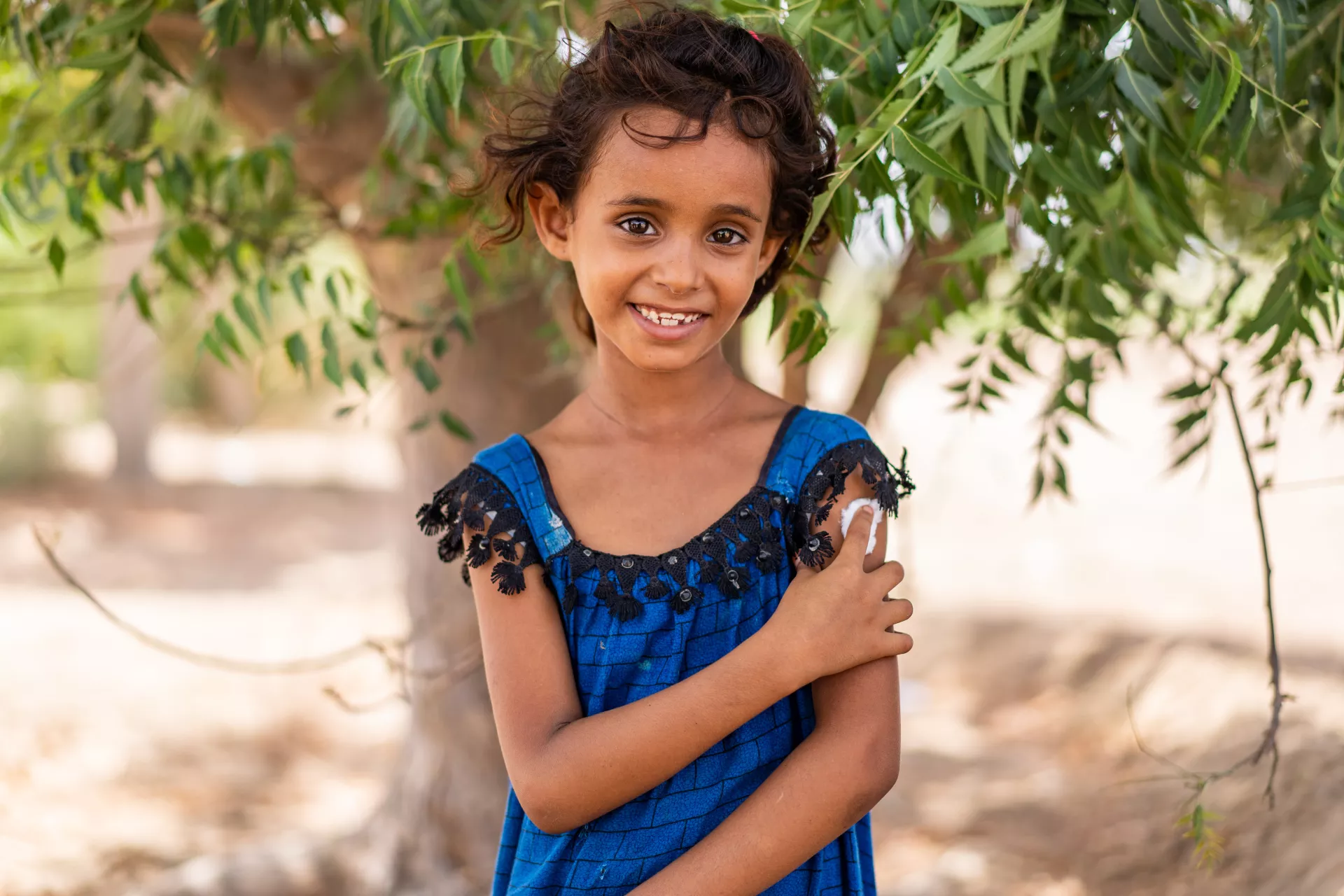 在也门的基层外展服务支持下，7岁的海因德·阿里·纳赛尔(Hind Ali Nasser)在接种疫苗后按着手臂上的接种部位。
