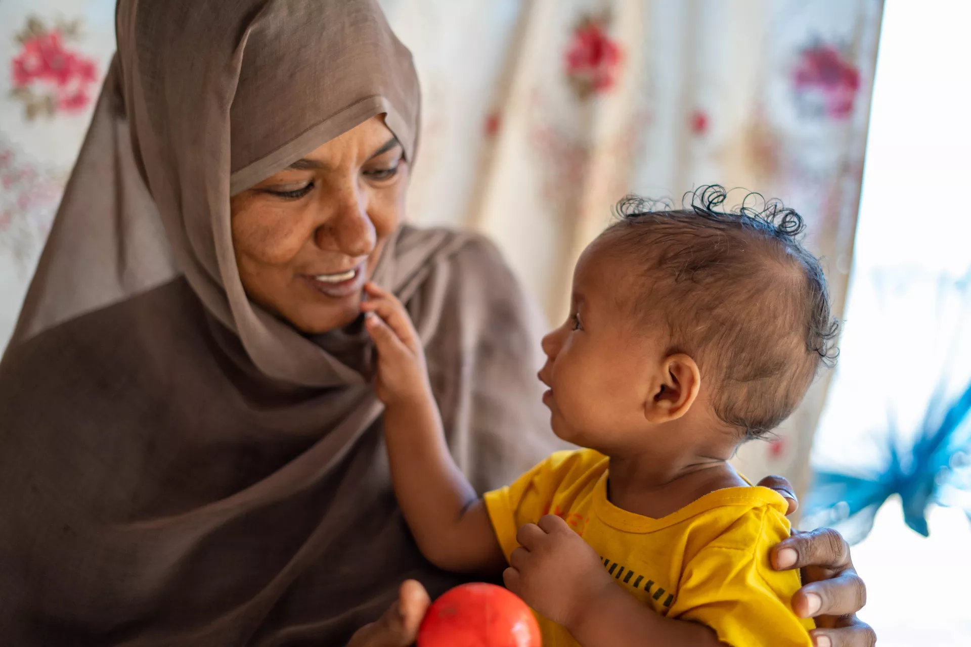 On 22 February 2023, Sabna Mohamed plays with her 9-month-old daughter, Fatuma, at their home in Wager village, North Delta locality, Kassala State, Sudan.