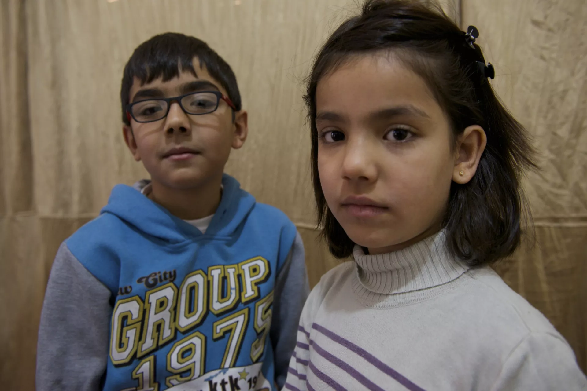 On 21 December 2013 in the Syrian Arab Republic, (left-right) Ammar, 11, and his sister Raama, 8, stand in their two-room shelter in a former private hospital, where internally displaced people are currently staying. 