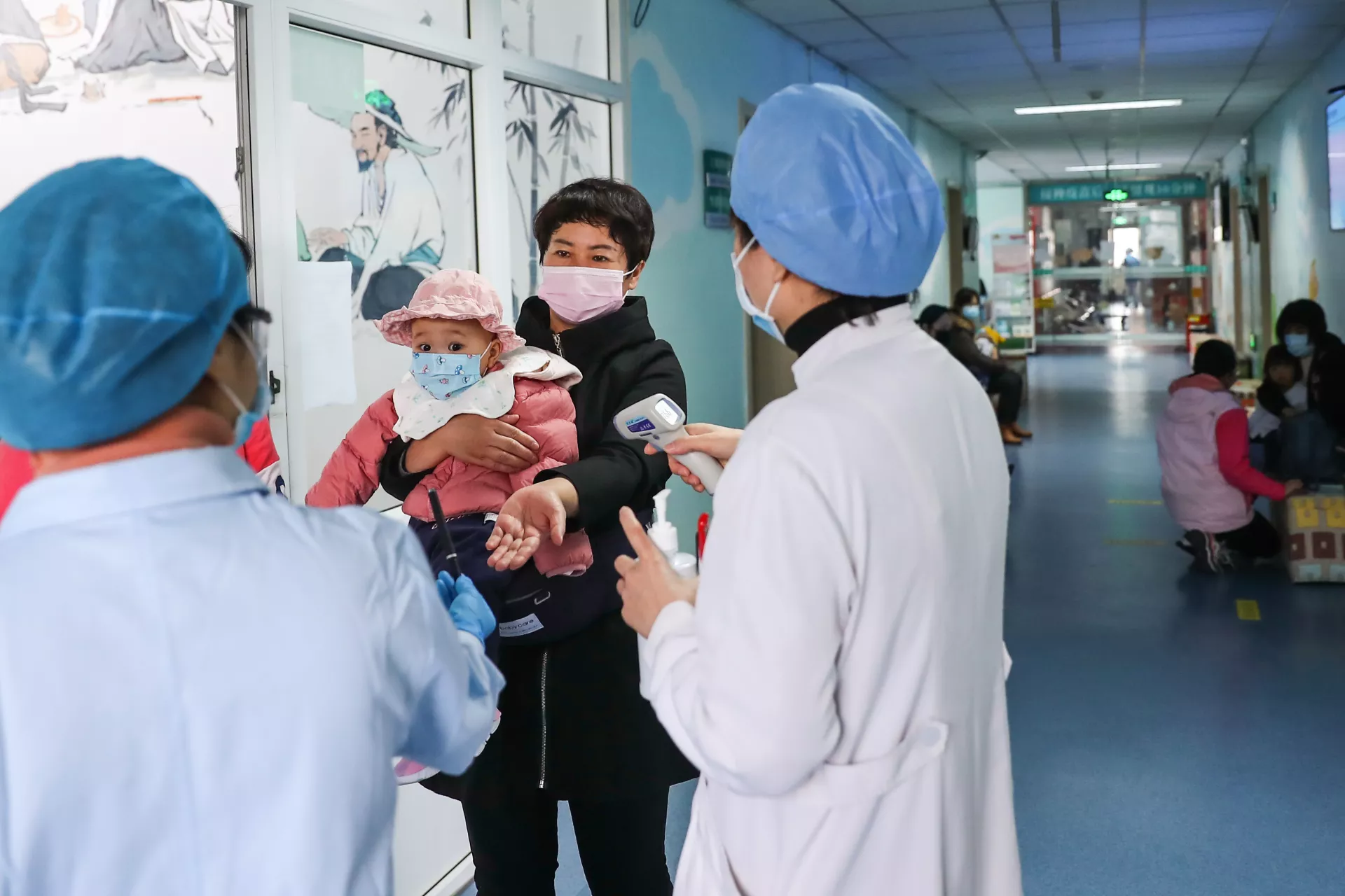 2020年3月26日，中国北京的一个社区卫生服务中心，护士为一名带孩子接种疫苗的照料人测量体温。