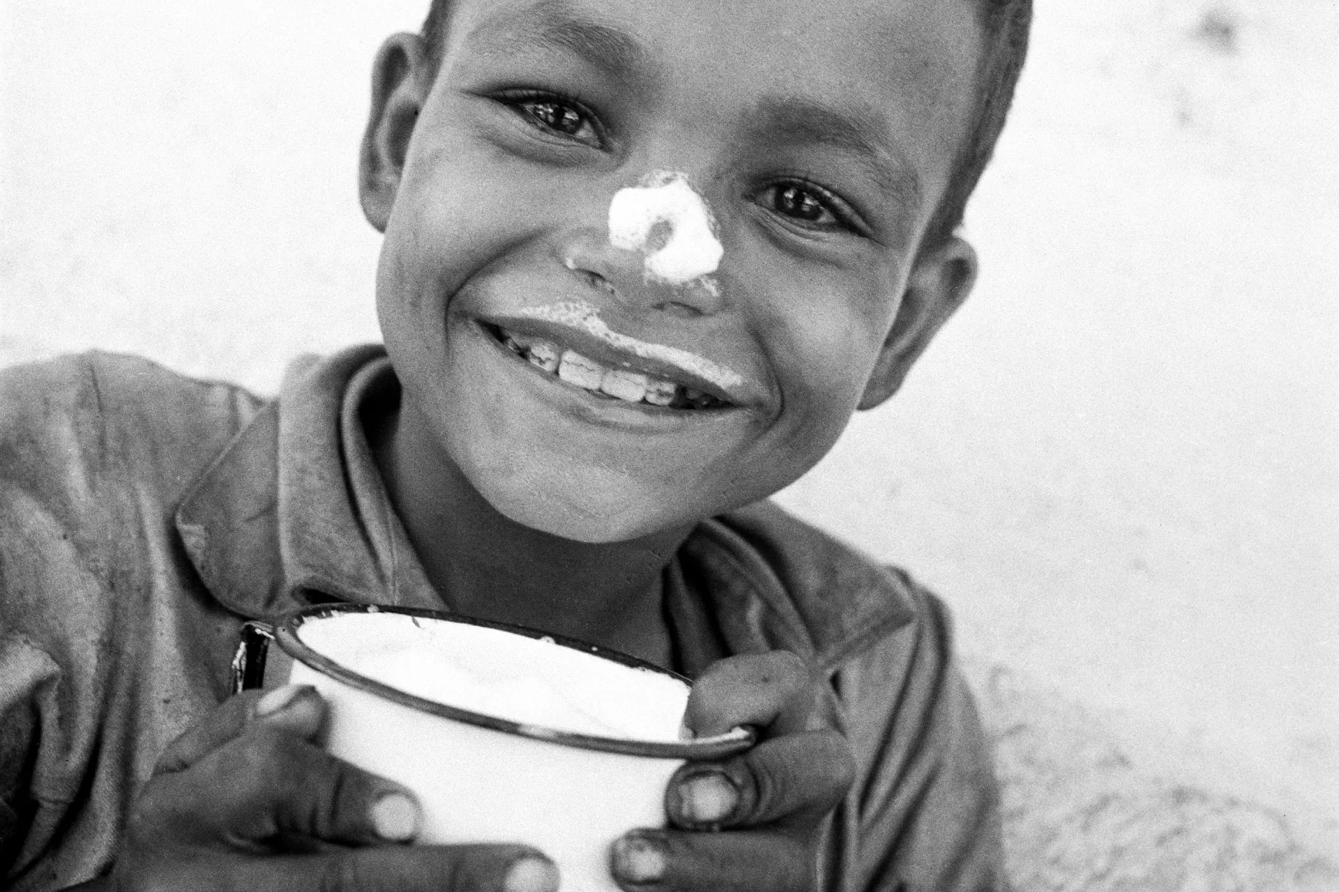 一名8岁的危地马拉男孩在饮用了联合国儿童基金会提供的牛奶后，在鼻子和嘴唇上留下了痕迹。