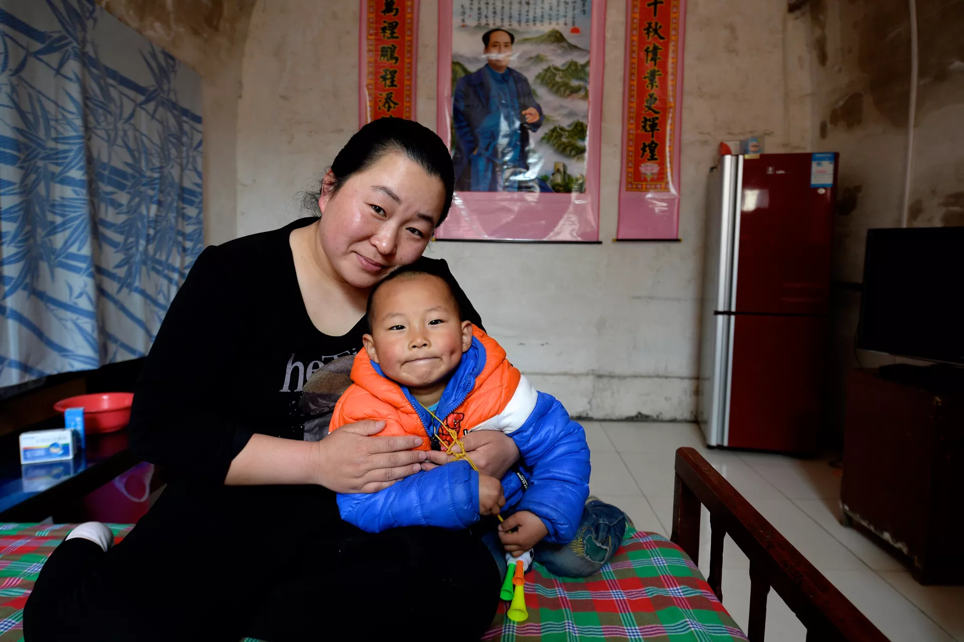 2017年，在山西省汾西县，一名母亲与孩子在家里。
