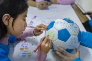 2022年11月5日，在联合国儿童基金会驻华办事处，一名儿童在足球上绘画，以表达她对儿童权利的看法。