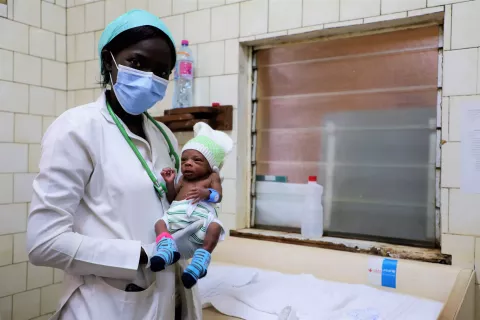 Germaine, a neonatology student at the Beroua regional hospital in Cameroon, holds a premature baby wearing an electronic bracelet that sends an alert if there is a drop in body temperature.