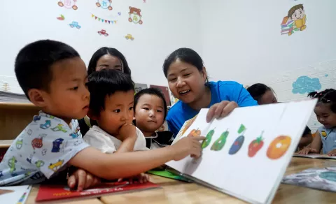 A volunteer captivates young children with picture books at the early childhood development (ECD) centre of Chengxi Community in Zhang County on 2 August, 2023.