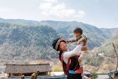 Xiong Li, a 26-year-old mother in Southwest China's Yunnan Province, holds her baby up.