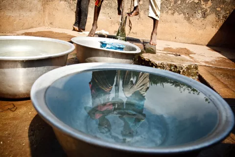 Children fill containers with water from a communal foot-activated pump, in the village of Kiendi-Walogo, Zanzan Region.