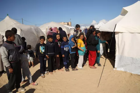 在加沙地带南部拉法市，几名儿童站在一个由联合国儿童基金会支持的儿科医生帐篷诊所入口处，等待测量中上臂围(MUAC)，这是针对他们营养不良筛查的部分工作。