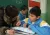 北京一所打工子女学校的老师给一名学生指导功课。