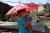 在被超级台风“海燕”侵袭的塔克洛班城，一名妇女打着伞，抱着她的女儿，路过一片废墟。