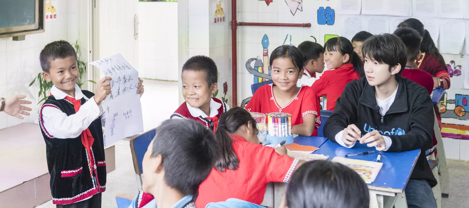 2019年7月13日，在云南省沧源县班老乡新寨小学，学生们就如何帮助受欺凌者展开小组讨论，一名学生将讨论结果展示给全班同学。