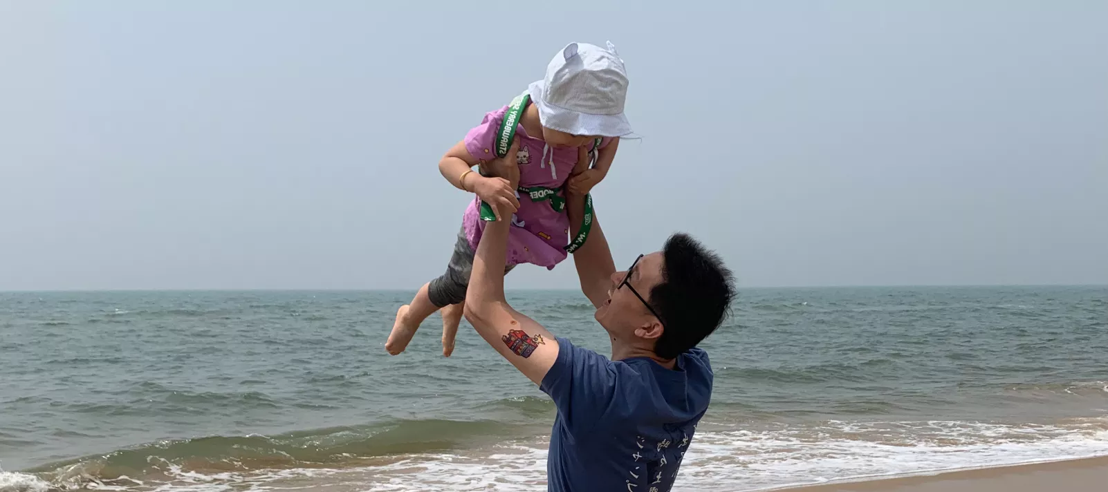 2019年，在河北省秦皇岛，一名父亲将孩子高高举起。