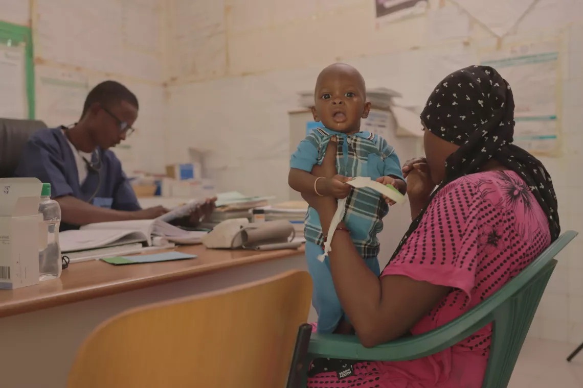 拉内鲁弗洛省的一名护士长桑巴·巴（Samba Ba）（左）为一名患有营养不良的儿童提供治疗。
