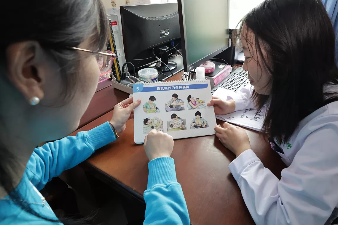 Zhu Xinya (left), Nutrition Officer at UNICEF China, and a health worker look at the UNICEF-developed Infant and Young Child Feeding (IYCF) counseling cards at the Taizi Township Health Centre in Huzhu Tu Autonomous County, Qinghai Province of China, on 17 August 2023.