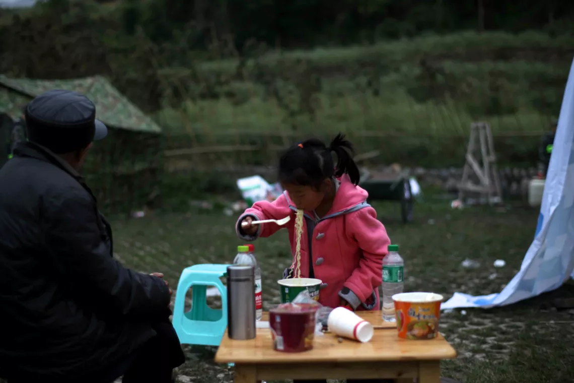 April 21, 2013, a child eating instant noodles in a temporary settlement area, Longdong township.