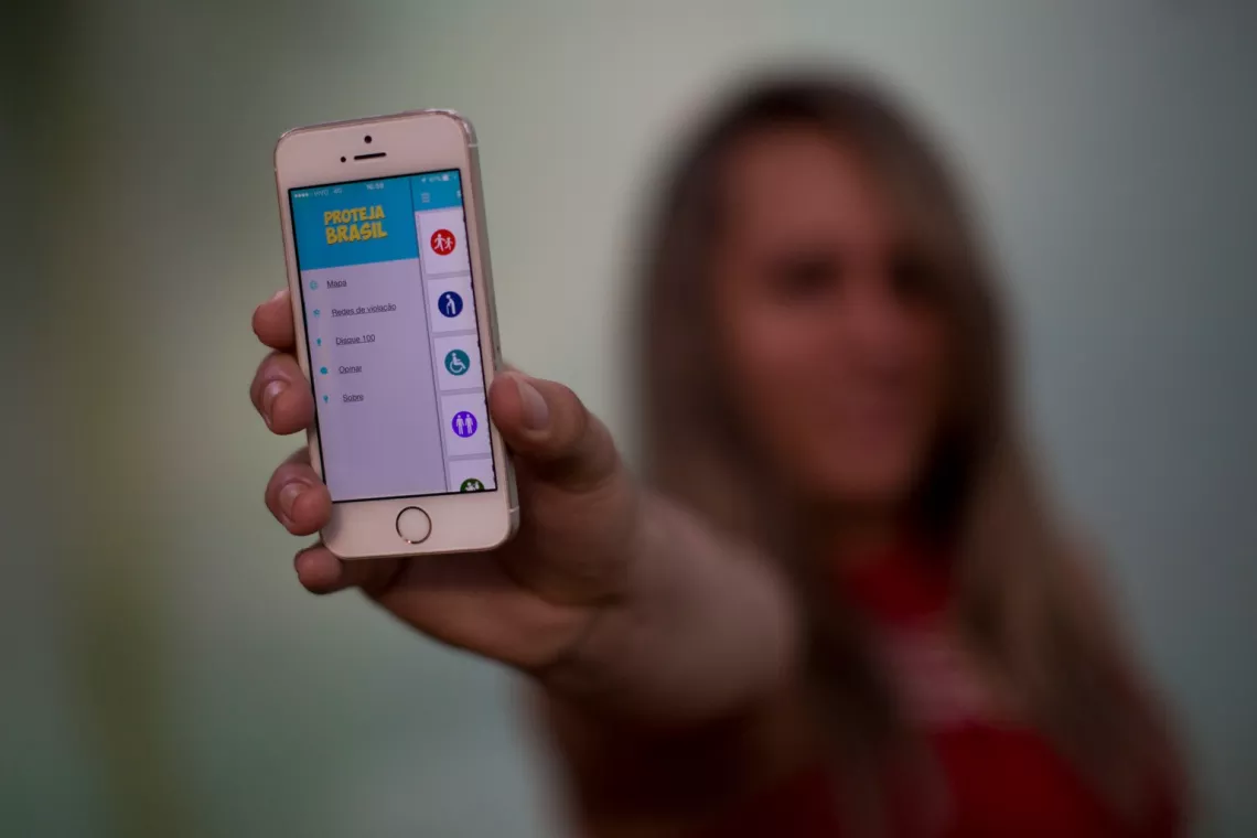 The ‘Proteja Brasil’ (Protect Brazil) app for smartphones and tablets, seen on a woman’s phone in Fortaleza City, facilitates reporting violence against children to authorities.