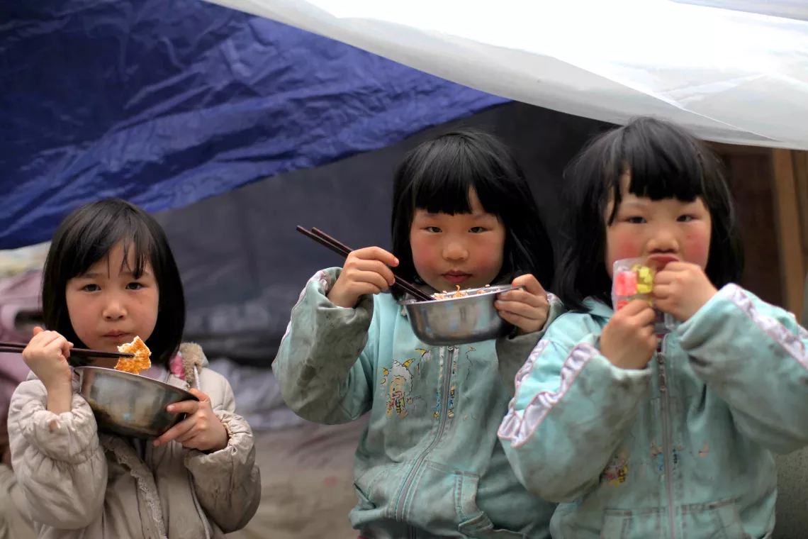 April 22, 2013, children eating in front of a tent in a temporary settlement area in Baoxing County.