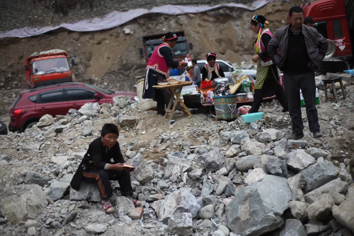 2013年4月22日，四川省宝兴县，房屋和道路在地震中遭到严重毁坏，一个男孩坐在石头上。