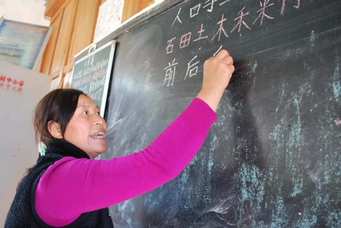  Xiong, aged 43, writes characters on the blackboard.